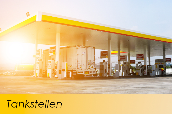 Bild zeigt eine gelbe Tankstelle mit Sonnenuntergrang und einem LKW beim Tanken